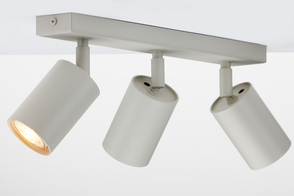 Lampa sufitowa Zoom z trzema spotami GU10 w kolorze szarym beżowym. Ujęcie z boku, z lampami ustawionymi pod różnymi kątami. Metalowa konstrukcja, matowe wykończenie, widoczne żarówki w otworach. Prosta, nowoczesna forma.