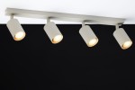 Lampa sufitowa Zoom w kolorze szarym beżowym z czterema reflektorami GU10. Ujęcie z dołu, ukazujące cylindryczne klosze o średnicy średniej i ciepłym świetle. Montaż na płaskiej powierzchni, na tle czarnym.