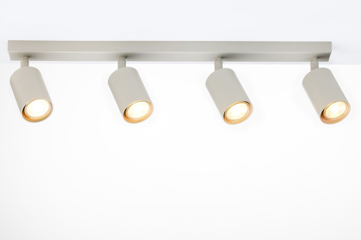 Lampa sufitowa Zoom w kolorze szarym beżowym z czterema spotami GU10. Ułożona poziomo, z widocznymi zaokrąglonymi kloszami o złotych wnętrzach, zamocowana na prostokątnej podstawie. Tło białe, co podkreśla kolor lampy.