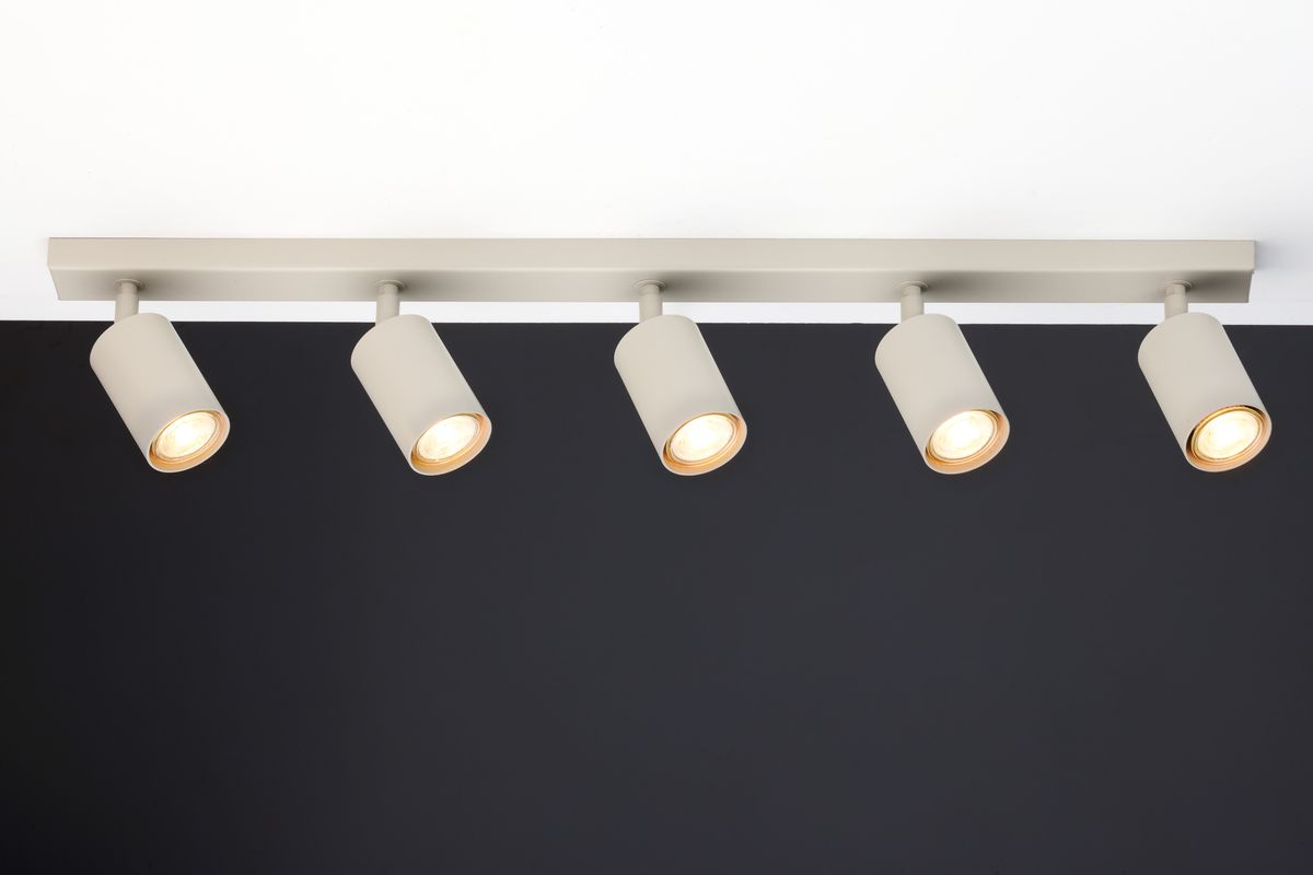 Lampa sufitowa Zoom w kolorze szarym beżowym, z pięcioma reflektorami GU10. Ułożona na prostokątnej belce, z widocznymi włączonymi żarówkami. Tło ciemne, co podkreśla delikatny kolor lampy.