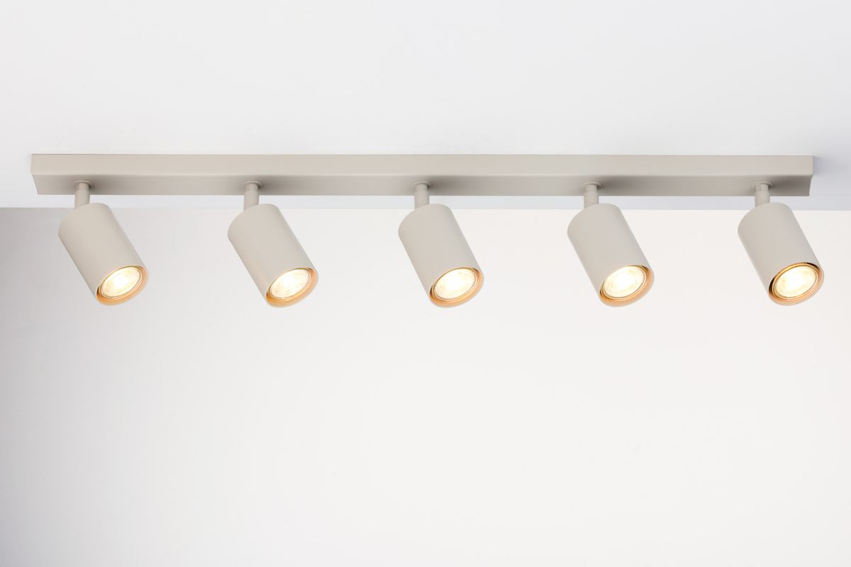 Sufitowa lampa spotowa w kolorze szarym beżowym z pięcioma oprawami GU10. Ujęcie frontalne, lampa zamontowana na prostokątnej listwie. Widoczne ciepłe światło z każdej oprawy. Proste tło, podkreślające minimalistyczny design.