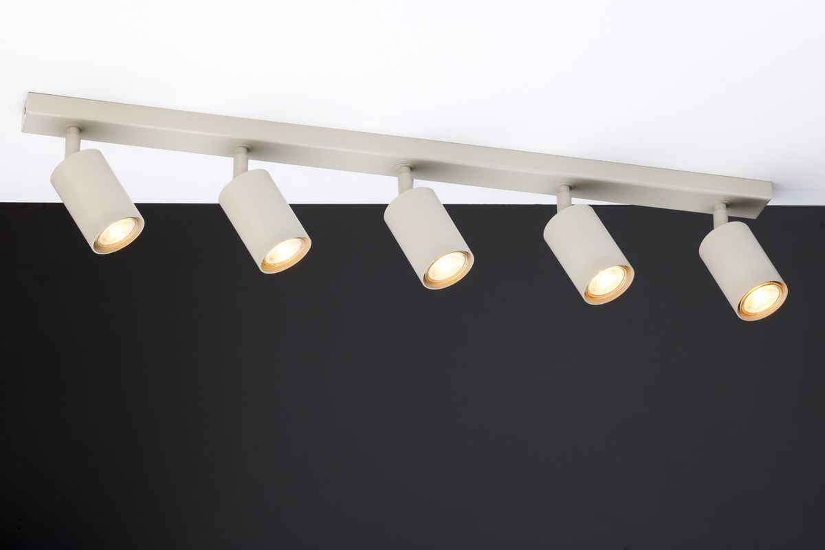 Lampa sufitowa Zoom z pięcioma spotami GU10 w kolorze szarym beżowym. Ułożona równolegle do sufitu, z cylindrycznymi kloszami skierowanymi w dół, na tle ciemnej ściany. Prosta, nowoczesna konstrukcja, idealna do oświetlenia wnętrz.