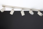 Lampa sufitowa Zoom w kolorze szarym beżowym z pięcioma reflektorami GU10. Ujęcie z boku, mocowana do sufitu. Reflektory są cylindryczne, skierowane w różnych kierunkach, na tle ciemnej ściany.