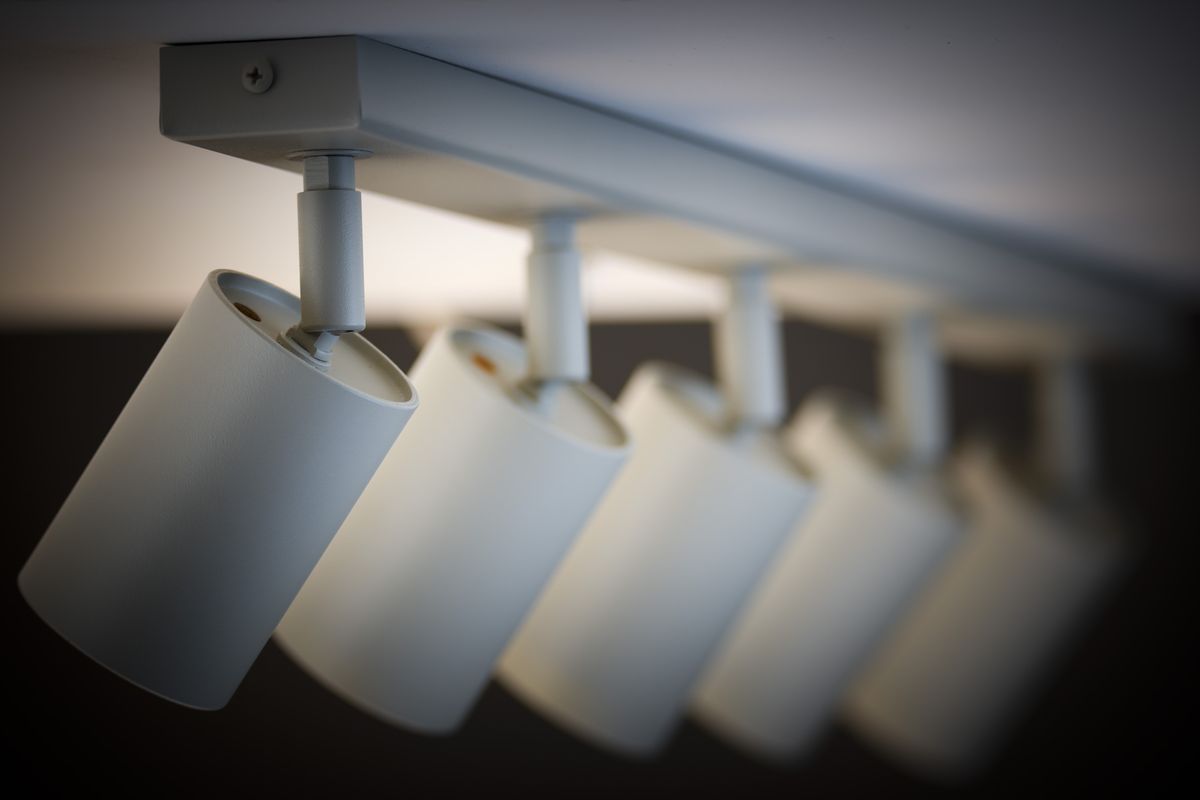 Lampa sufitowa Zoom z pięcioma reflektorami GU10 w kolorze szarym beżowym. Reflektory umieszczone na prostokątnej podstawie, ustawione pod kątem, co umożliwia skierowanie światła w różne miejsca. Prosty, nowoczesny design.