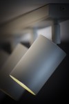 Lampa sufitowa Zoom w kolorze szarym beżowym, z pięcioma regulowanymi spotami GU10. Ujęcie z boku, ukazujące jeden z reflektorów w pozycji pod kątem, emitujący ciepłe światło. Prosta, cylindryczna forma z matowym wykończeniem.