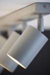 Lampa sufitowa Zoom w kolorze szarym beż, z pięcioma spotami GU10. Ujęcie z boku, zbliżenie na jeden z reflektorów, o cylindrycznym kształcie, zamocowany na metalowej podstawie. Jasne światło wydobywa się z oprawy.