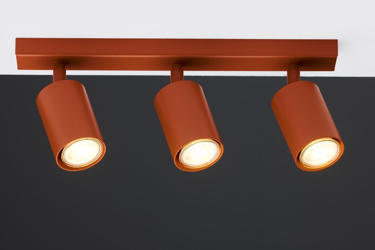 Lampa sufitowa Zoom z trzema reflektorami GU10 w kolorze ceglastym, zamontowana na prostokątnej, matowej podstawie. Reflektory mają cylindryczny kształt, skierowane w dół, na jednolitym tle, co podkreśla ich design.
