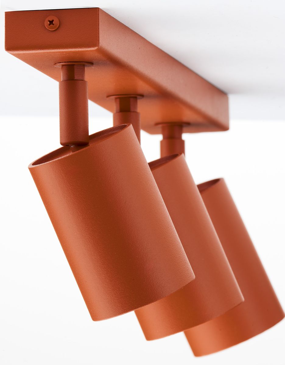 Lampa sufitowa Zoom w kolorze ceglastym z trzema reflektorami GU10. Ujęcie z dołu, pokazujące okrągłe, matowe klosze zamocowane na prostokątnym stelażu. Całość umieszczona na białym tle, co podkreśla intensywność koloru.