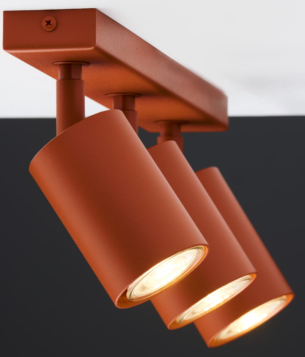 Lampa sufitowa Zoom w kolorze ceglanym z trzema reflektorami GU10. Reflektory mają cylindryczny kształt i są zawieszone na prostokątnej podstawie. Ujęcie z góry, pokazujące detale i krawędzie lampy na jednolitym tle.