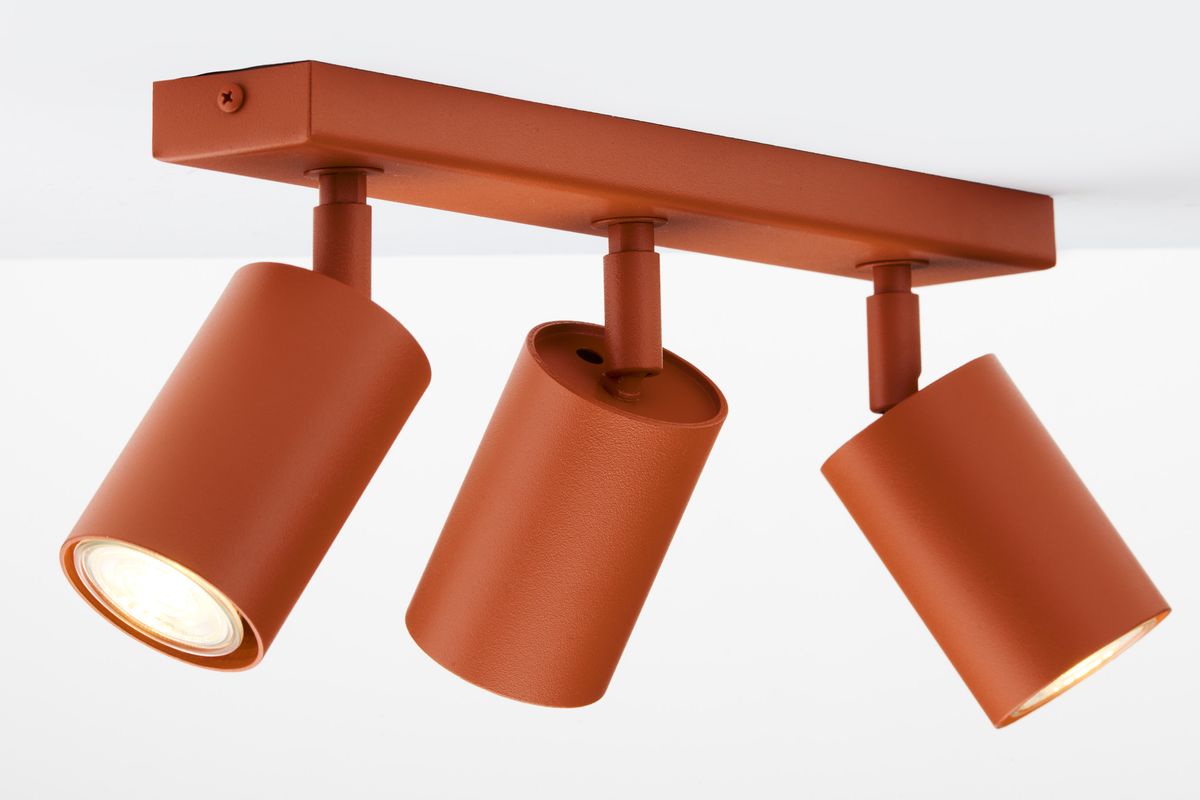 Lampa sufitowa Zoom w kolorze ceglastym z trzema ruchomymi reflektorami GU10. Ujęcie z boku, ukazujące cylindryczny kształt kloszy i metalową konstrukcję. Produkt zamontowany na suficie, z widocznymi detalami mocowania.
