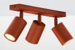 Lampa sufitowa Zoom w kolorze ceglastym z trzema ruchomymi reflektorami GU10. Ujęcie z boku, pokazujące okrągłe klosze z metaliczną fakturą, zamontowane na prostokątnej podstawie. Reflektory skierowane w różne strony, gotowe do oświetlenia przestrzeni.