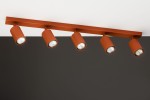 Lampa sufitowa Zoom w kolorze ceglastym z pięcioma reflektorami GU10. Ujęcie z dołu, pokazujące lampę zamontowaną na prostej, poziomej listwie. Reflektory mają cylindryczny kształt i są skierowane w różnych kierunkach. Tło w ciemnym kolorze.