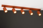 Lampa sufitowa Zoom w kolorze ceglastym z pięcioma reflektorami GU10, zamontowana na prostokątnej listwie. Reflektory mają okrągłe kształty i emitują ciepłe światło. Ujęcie z góry pokazuje ich rozmieszczenie na ciemnym tle.