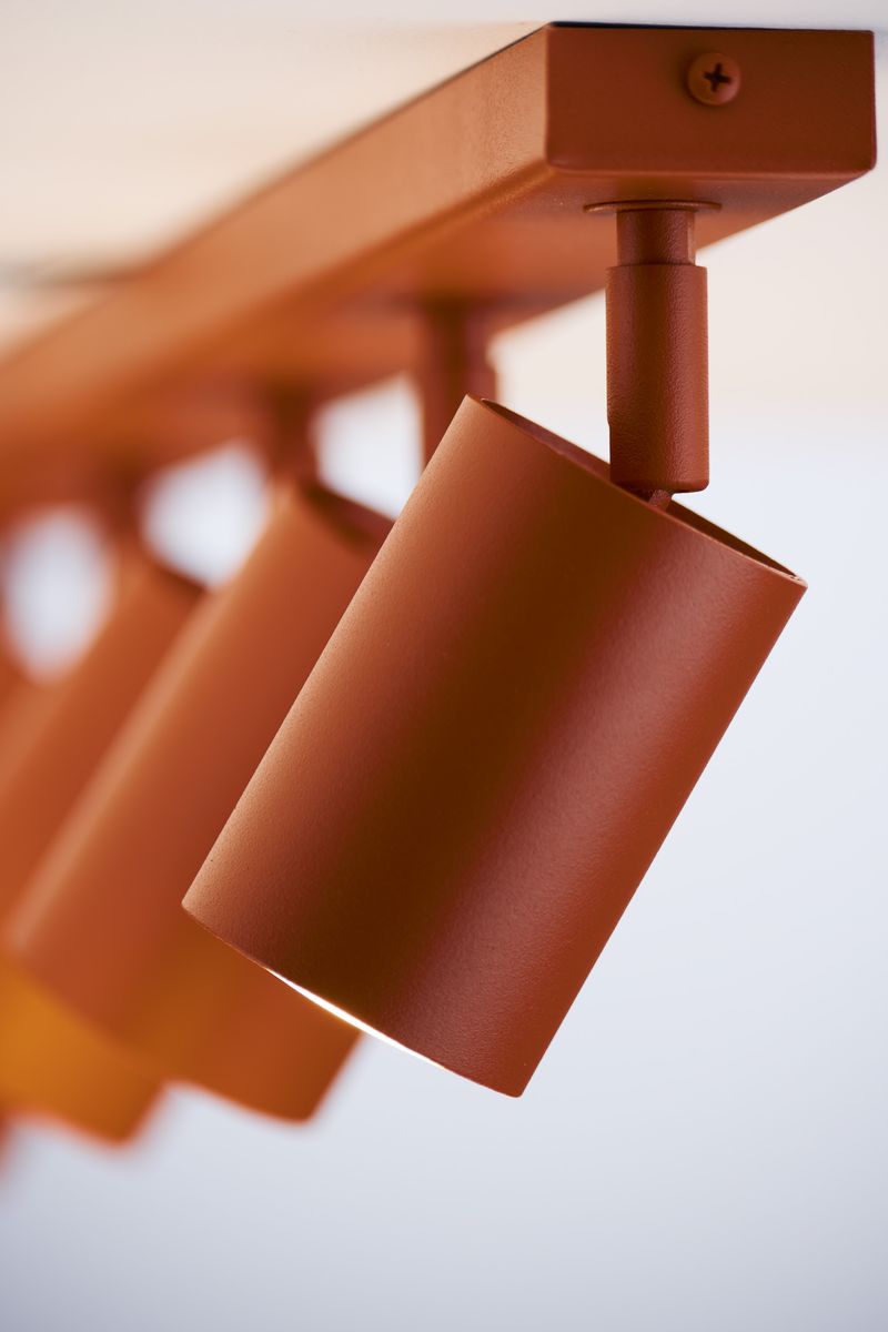 Lampa sufitowa Zoom w kolorze ceglastym, z pięcioma ruchomymi reflektorami GU10. Ujęcie z boku, ukazujące cylindryczne klosze o matowej fakturze, zamontowane na prostokątnej podstawie. Prosta, nowoczesna forma, idealna do oświetlenia wnętrz.