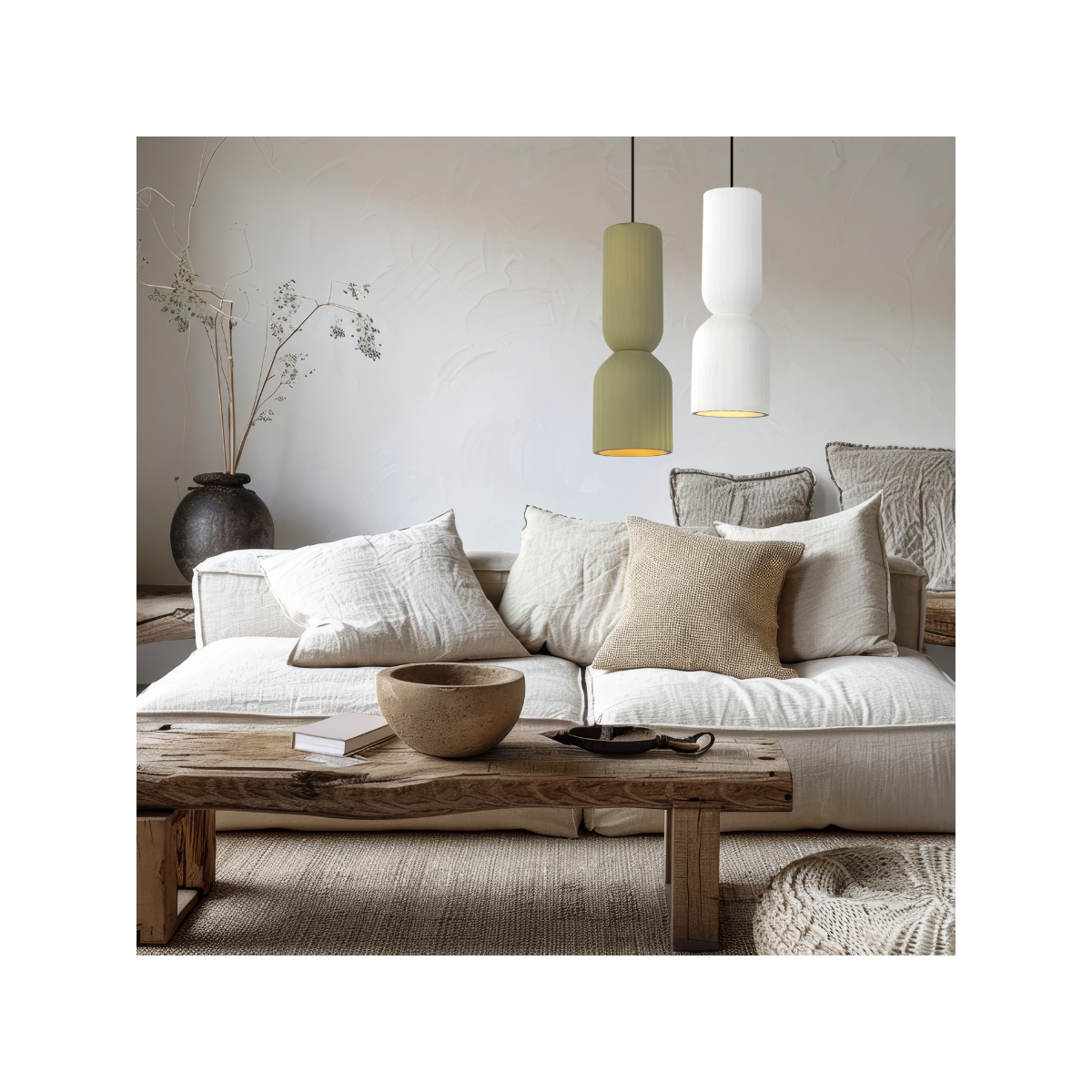 Lampa wisząca Balera z białym kloszem, zawieszona nad sofą w jasnym wnętrzu. Widoczny również stół z drewnianym blatem, ceramiczna miska i poduszki w neutralnych odcieniach. Tło o gładkiej teksturze, z delikatnymi dekoracjami roślinnymi.