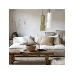 Lampa wisząca Balera z białym kloszem, zawieszona nad sofą w jasnym wnętrzu. Widoczny również stół z drewnianym blatem, ceramiczna miska i poduszki w neutralnych odcieniach. Tło o gładkiej teksturze, z delikatnymi dekoracjami roślinnymi.