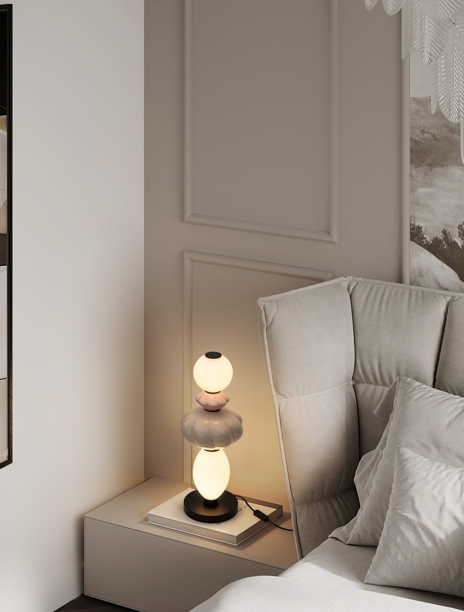 Lampa stołowa Casurno z jedną żarówką LED 16W, w kolorze czarnym z multikolorowymi elementami. Ustawiona na stoliku obok łóżka, z przezroczystymi kulami i opalizującym kloszem, tworzy nowoczesny akcent w aranżacji wnętrza.
