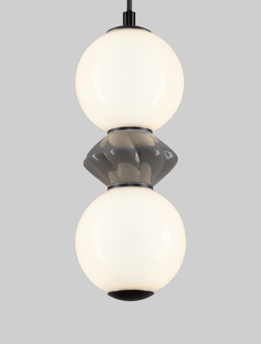 Lampa wisząca Monreta z jednym źródłem LED 10W. Posiada dwie białe, okrągłe kule ze szkła, umieszczone na szarym, diamentowym elemencie. Klosze są zawieszone na czarnym kablu, na szarym tle.