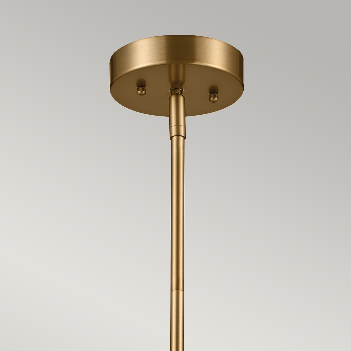 Lampa wisząca Luella z mosiężnym, okrągłym mocowaniem sufitowym i prostym, metalowym stelażem. Wysoka, minimalistyczna konstrukcja z miejscem na trzy źródła światła E14. Tło jasne, co podkreśla elegancki charakter lampy.