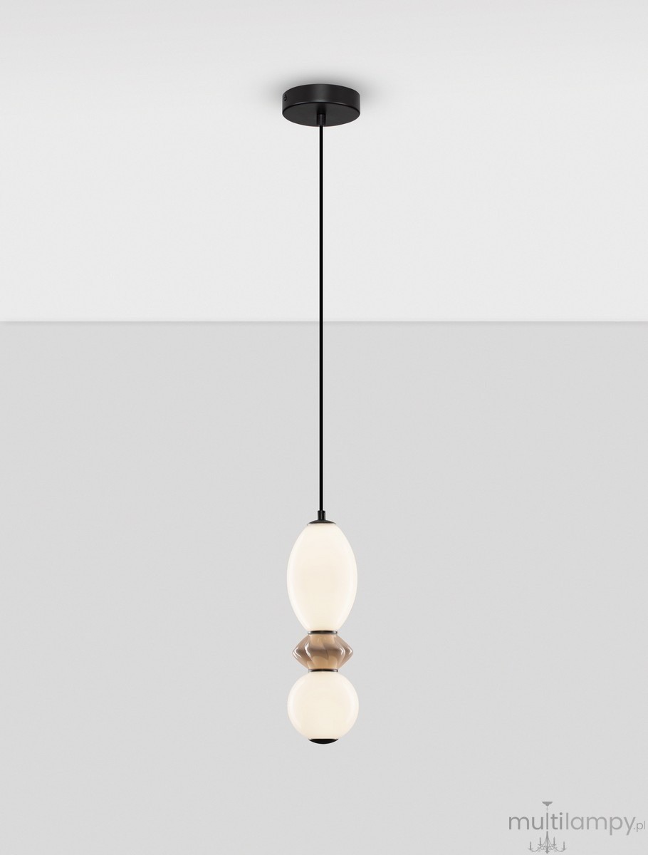 Lampa wisząca Monreta w kolorze czarnym i mokka, z jedną żarówką LED 12W. Okrągła podsufitka, cienki kabel, ażurowa konstrukcja z mlecznego szkła w kształcie elipsy. Zawieszona w pionie, na jasnoszarym tle.