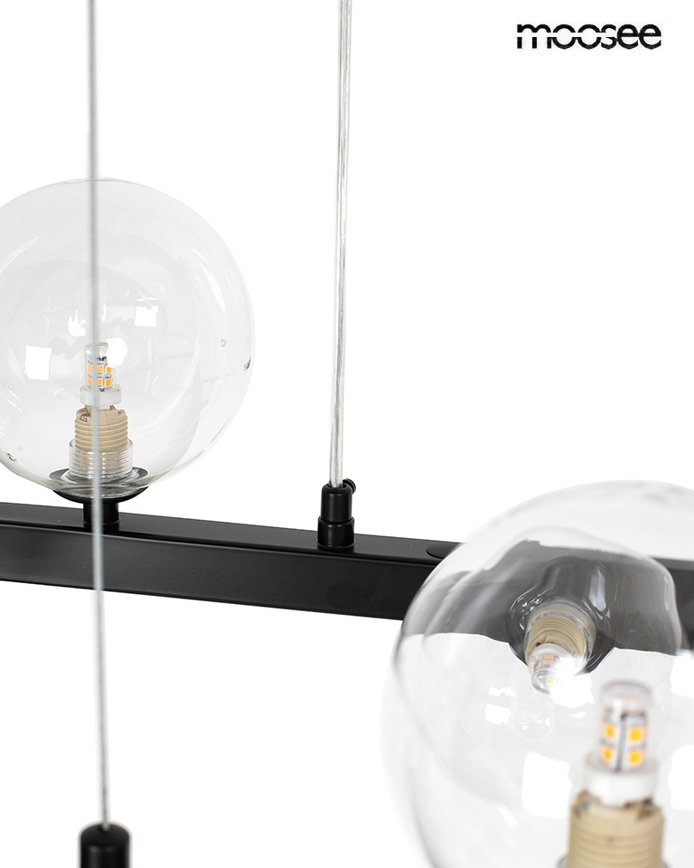 Lampa wisząca Alure Oval 120 w kolorze czarnym z 20 miejscami na żarówki G9. Konstrukcja z metalowym stelażem i szklanymi kloszami w kształcie kul. Wisi na przezroczystych linkach, ukazując nowoczesny design.