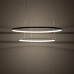 Lampa wisząca LED Circolo D60 o dwóch okrągłych pierścieniach w kolorze białym, zawieszona na cienkich linkach. Emituje ciepłe światło o temperaturze 3000K, tworząc subtelne cienie na ścianie. Idealna do nowoczesnych wnętrz.