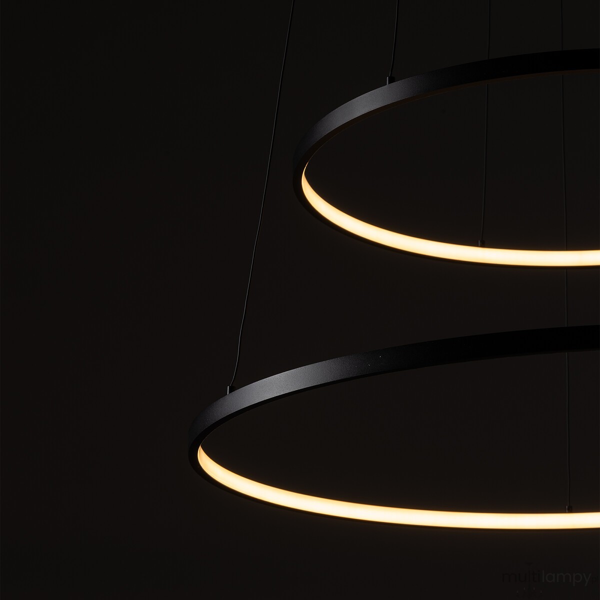 Lampa wisząca LED Circolo D60 o mocy 67W, w kolorze czarnym, z dwoma okrągłymi pierścieniami emitującymi ciepłe światło (3000K). Ujęcie z góry, detale krawędzi lampy na ciemnym tle, zawieszona na cienkich linach.