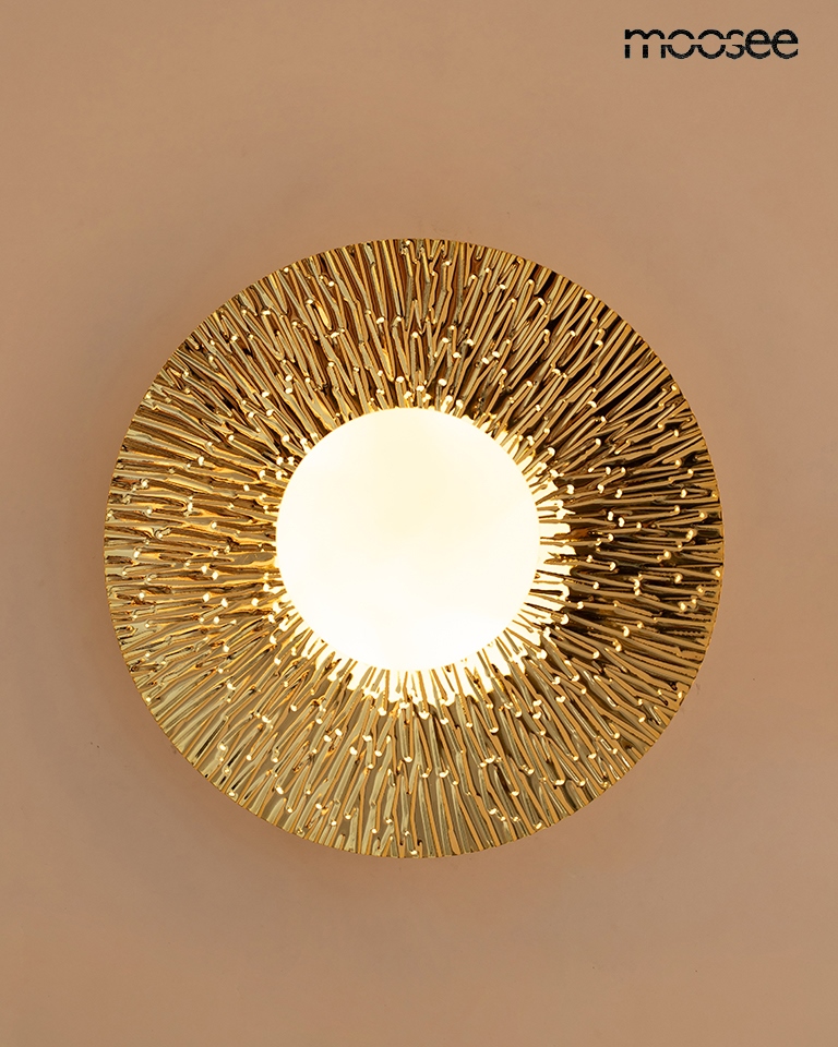 Kinkiet Soul 20 w kolorze złotym, z okrągłym, teksturowanym kloszem, z wyraźnym wzorem promieni. Umożliwia montaż jednej żarówki G9. Widok frontalny, produkt zamontowany na ścianie, na jednolitym tle.