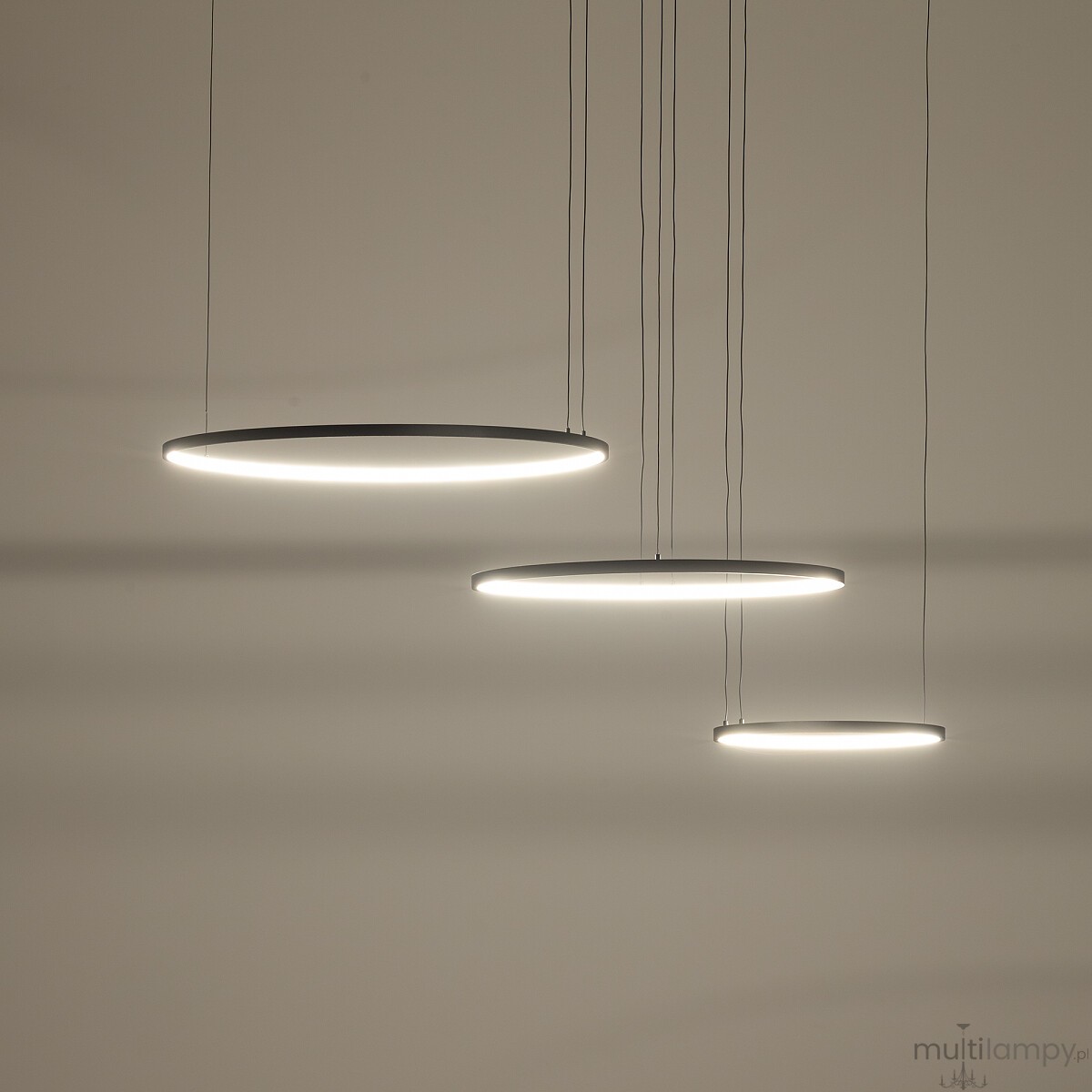 Lampa wisząca LED Circolo 85W, kolor czarny, z trzema okrągłymi kloszami zawieszonymi na cienkich linkach. Klosze emitują ciepłe światło 3000K, zawieszone na różnej wysokości, na jednolitym tle.