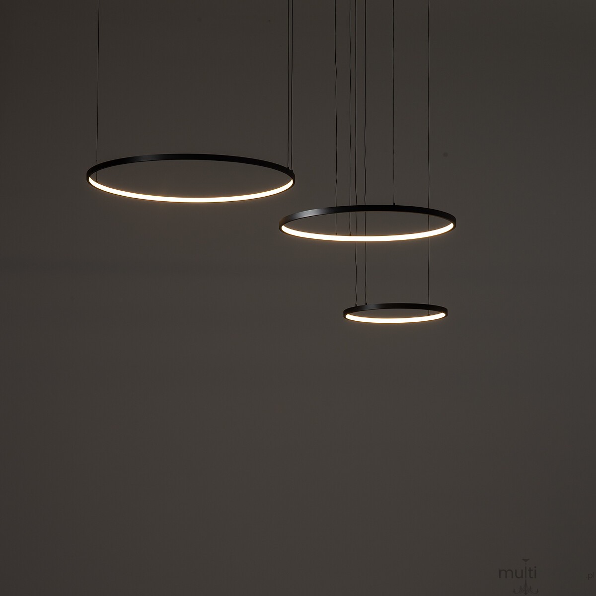 Lampa wisząca LED Circolo 85W 3000K w kolorze czarnym, składająca się z trzech okrągłych pierścieni o różnej średnicy, zawieszonych na cienkich linkach. Delikatne światło LED otacza pierścienie, tworząc nowoczesny efekt wizualny.