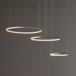 Lampa wisząca LED Circolo 85W, biała, z trzema okrągłymi, metalowymi pierścieniami o różnej średnicy, zawieszona na cienkich linkach. Źródło światła o temperaturze 3000K, idealna do nowoczesnych wnętrz. Tło w odcieniach szarości.