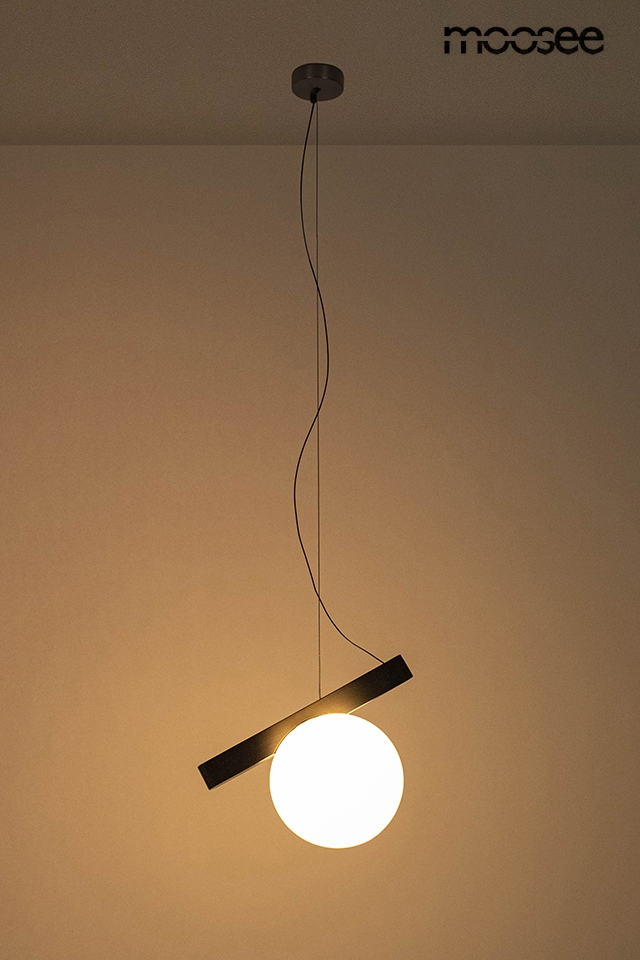 Lampa wisząca Balance 1xG9 w kolorze grafitowym, zawieszona na cienkim przewodzie. W centralnej części znajduje się okrągła, biała kula, a nad nią umieszczony jest prostokątny element w kolorze grafitowym. Tło jasne, jednolite.