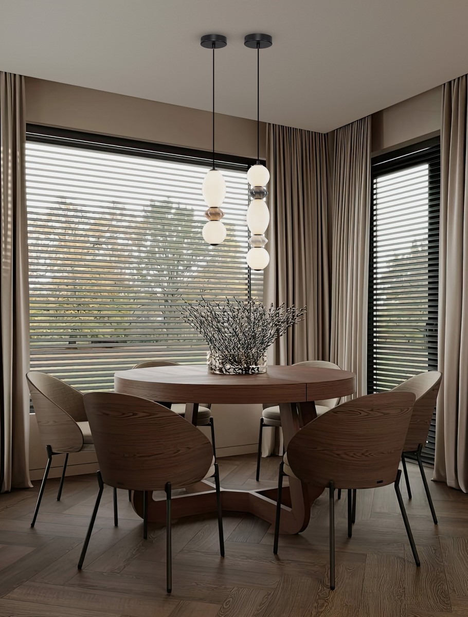 Lampa wisząca Monreta z jednym źródłem LED 14W, w kolorze czarnym, zawieszona na dwóch cienkich linkach. Posiada sześć szklanych kloszy w różnych kolorach, umieszczona nad okrągłym drewnianym stołem w eleganckim wnętrzu.