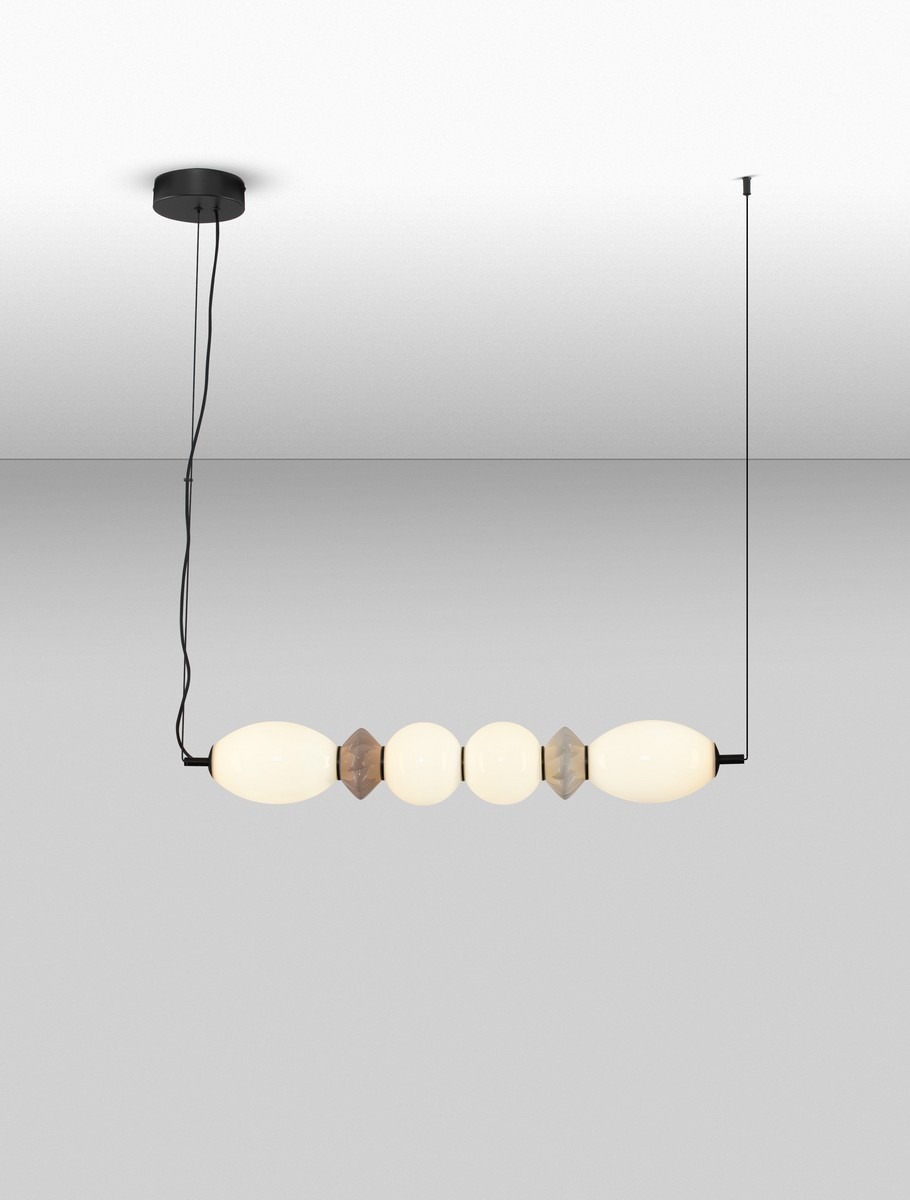 Lampa wisząca Monreta 1xLED 28W w kolorze czarnym z multikolorowymi elementami. Wydłużony kształt z okrągłymi i heksagonalnymi detalami, zawieszona na czarnym przewodzie, skierowana w dół. Tło jednolite, jasne.