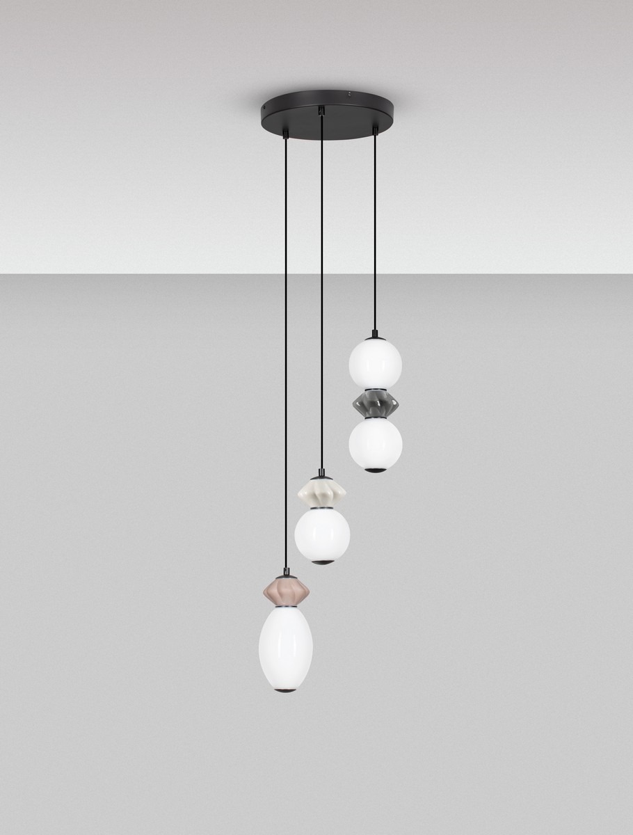 Lampa wisząca Monreta z trzema kloszami LED 20W w różnych kolorach, zwisająca na czarnych przewodach, z okrągłym, czarnym mocowaniem sufitowym. Klosze w formie kulistych i owalnych, z białym szkłem oraz dekoracjami w odcieniach szarości i beżu.