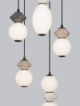 Lampa wisząca Monreta z pięcioma źródłami LED o mocy 28W. Szklane klosze w różnych kształtach, w kolorze białym i szarym, zawieszone na czarnych przewodach. Produkt wisi centralnie, na jednolitym szarym tle.