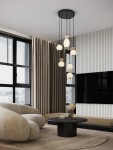 Lampa wisząca Monreta 5xLED 28W w kolorze czarnym, z pięcioma szklanymi kloszami w różnych kształtach i kolorach, zawieszona na cienkich linkach. Produkt znajduje się w nowoczesnym wnętrzu z beżową sofą i okrągłym stołem.