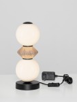 Czarna lampa stołowa Monreta z jedną żarówką LED 6W. Składa się z dwóch okrągłych kloszy w kolorze białym i brązowym, umieszczonych na czarnej, okrągłej podstawie. Widoczny kabel zasilający z włącznikiem. Tło neutralne, jasne.
