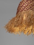 Lampa wisząca Fanliza z kloszem w kolorze naturalnym, z plecionką, wykończona frędzlami z trawy. Klosz ma okrągły kształt, podwieszony, z miejscem na żarówkę E27. Tło szare, minimalistyczne, podkreślające detal lampy.
