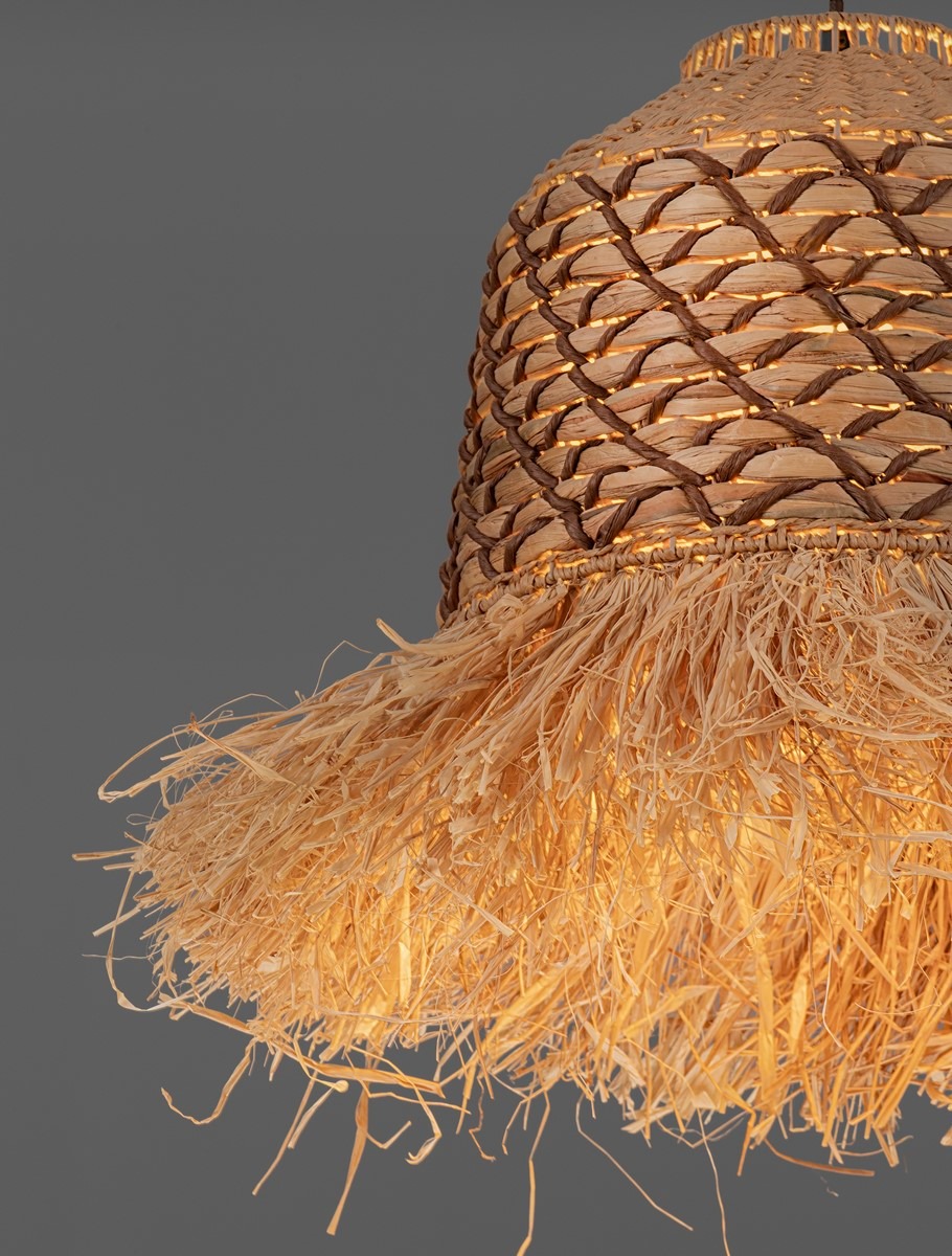 Lampa wisząca Fanliza z kloszem z plecionego hiacyntu wodnego w kolorze naturalnym, z frędzlami u dołu. Klosz ma okrągły kształt, a całość zawieszona jest na czarnej oprawie. Tło szare, minimalistyczne.