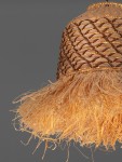 Lampa wisząca Fanliza z kloszem z plecionego hiacyntu wodnego w kolorze naturalnym, z frędzlami u dołu. Klosz ma okrągły kształt, a całość zawieszona jest na czarnej oprawie. Tło szare, minimalistyczne.
