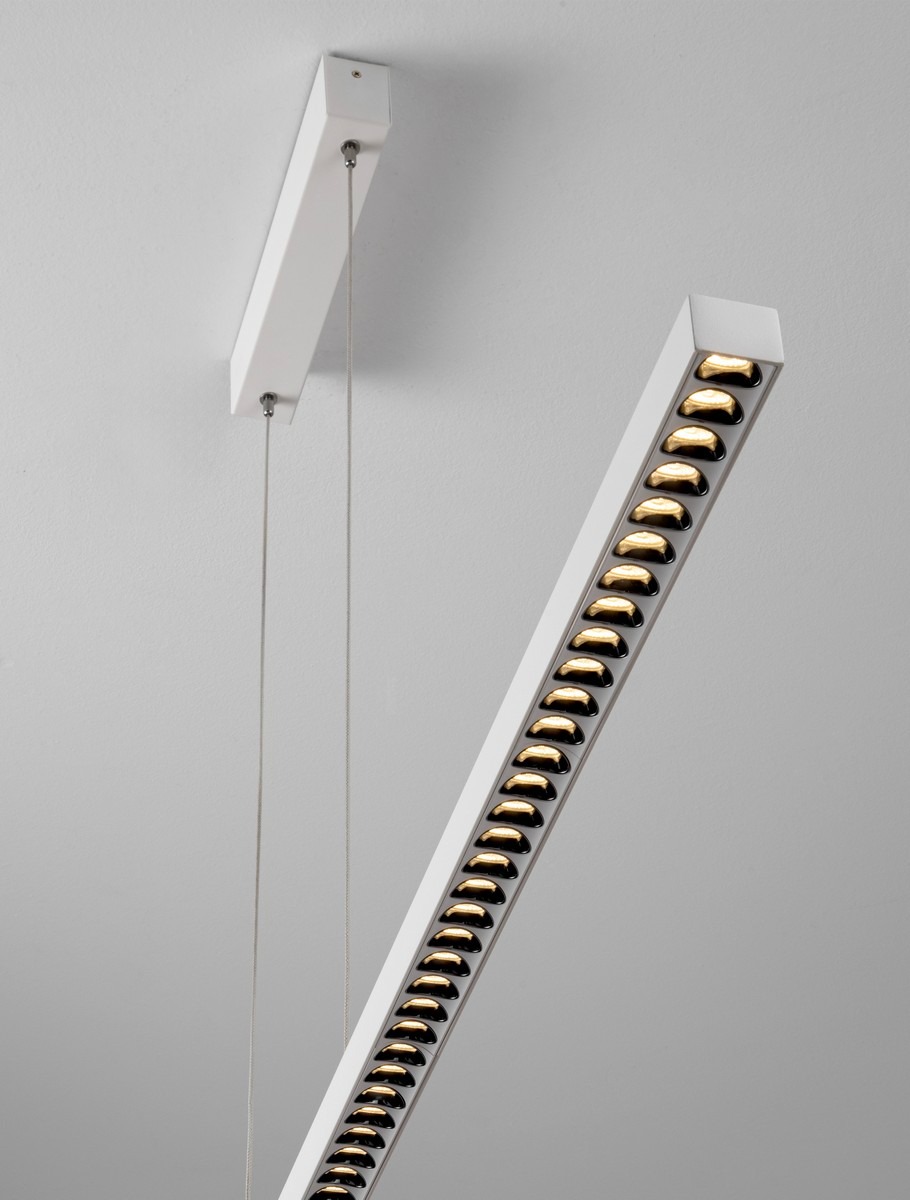 Lampa wisząca Tarvana 1xLED 27W w kolorze białym, z prostokątnym, minimalistycznym kształtem, zawieszona na cienkich linkach. Widoczne elementy oświetleniowe w złotym kolorze, montaż na suficie. Tło w jasnym odcieniu.