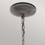 Lampa wisząca Taulbee z postarzanym cynkiem, zawieszona na metalowym łańcuchu. Widoczna górna część z okrągłym, płaskim sufitem. Elementy wykończeniowe w odcieniach szarości, idealna do stylowych wnętrz.