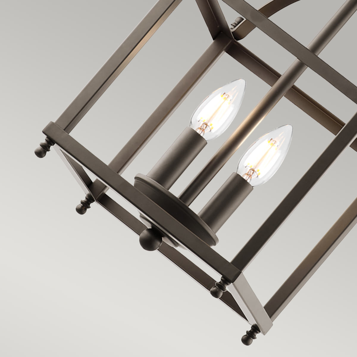 Larkin S lampa wisząca w kolorze stary brąz, z dwoma gniazdami E14, w kształcie prostokątnej klatki. Widoczne dwie żarówki o kształcie łezki. Ujęcie z góry, podkreślające detal konstrukcji i elegancki design.