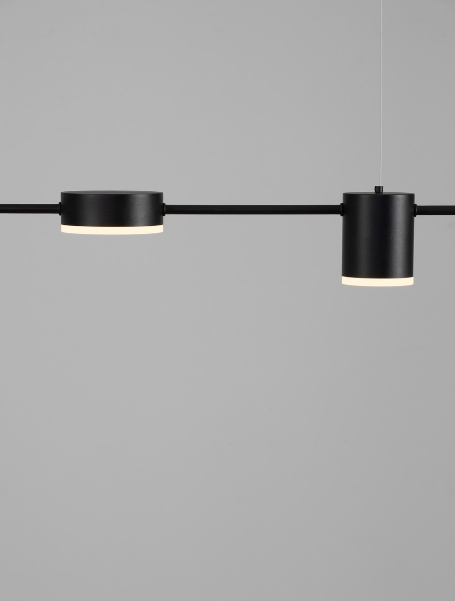 Lampa wisząca Orelvio z sześcioma źródłami LED 20W w kolorze czarnym. Posiada cylindryczne klosze o delikatnym podświetleniu, zawieszone na prostym, minimalistycznym ramieniu. Ujęcie frontalne, na jednolitym tle.