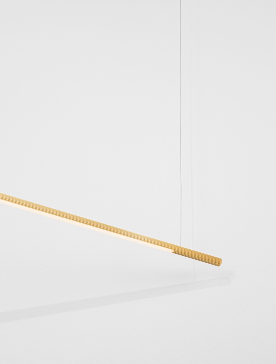 Lampa wisząca Monterzo z jedną żarówką LED 20W w złotym kolorze. Prosty, podłużny kształt z teksturowaną powierzchnią. Zawieszona na cienkim przewodzie, idealna do nowoczesnych wnętrz. Tło białe, co podkreśla elegancję lampy.