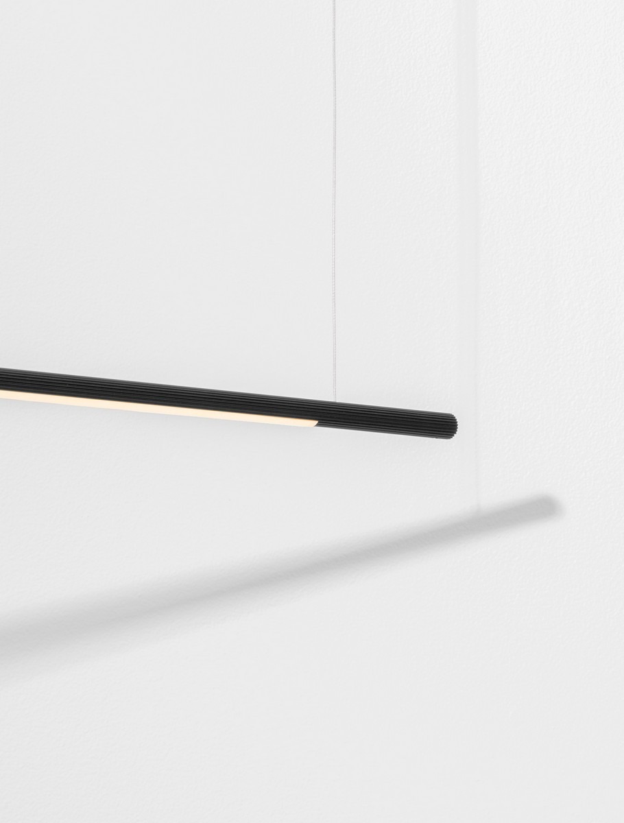 Lampa wisząca Monterzo w kolorze czarnym, minimalistyczna konstrukcja z jedną diodą LED 20W. Ujęcie z boku, widoczna smukła forma oraz ciepłe światło emitowane z górnej krawędzi. Tło białe, podkreślające elegancki design.