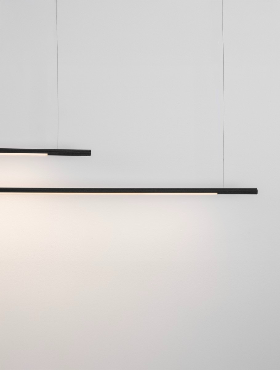 Lampa wisząca Monterzo 2xLED 40W CCT w kolorze czarnym, w minimalistycznym stylu. Dwa długie, proste klosze zawieszone na cienkich przewodach, emitujące ciepłe światło. Ujęcie frontalne, na jednolitym, jasnym tle.