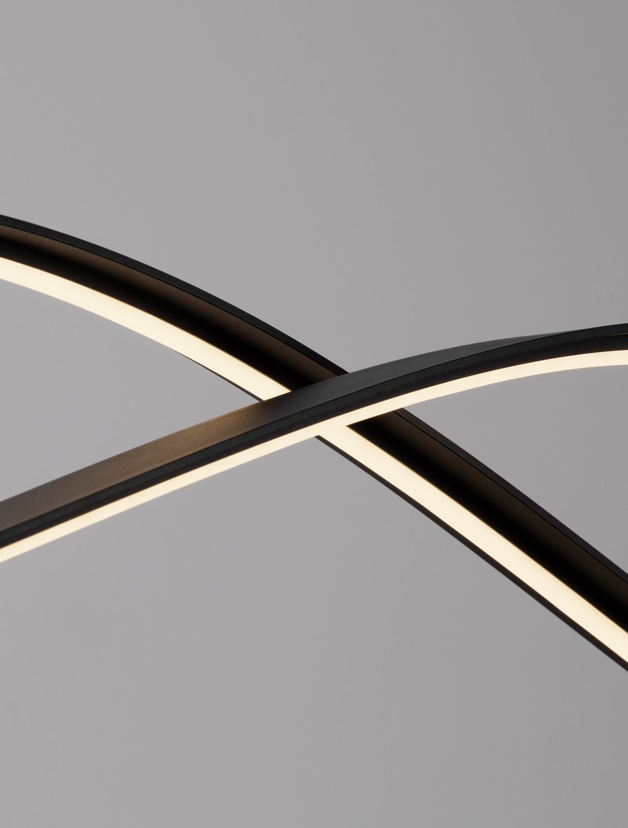 Lampa wisząca Cirvela 2xLED 27W CCT w kolorze czarnym, złożona z dwóch zakrzywionych elementów. Widoczny delikatny, podświetlony pas LED wzdłuż krawędzi. Ujęcie z bliska podkreślające kształt i fakturę materiału. Tło szare.