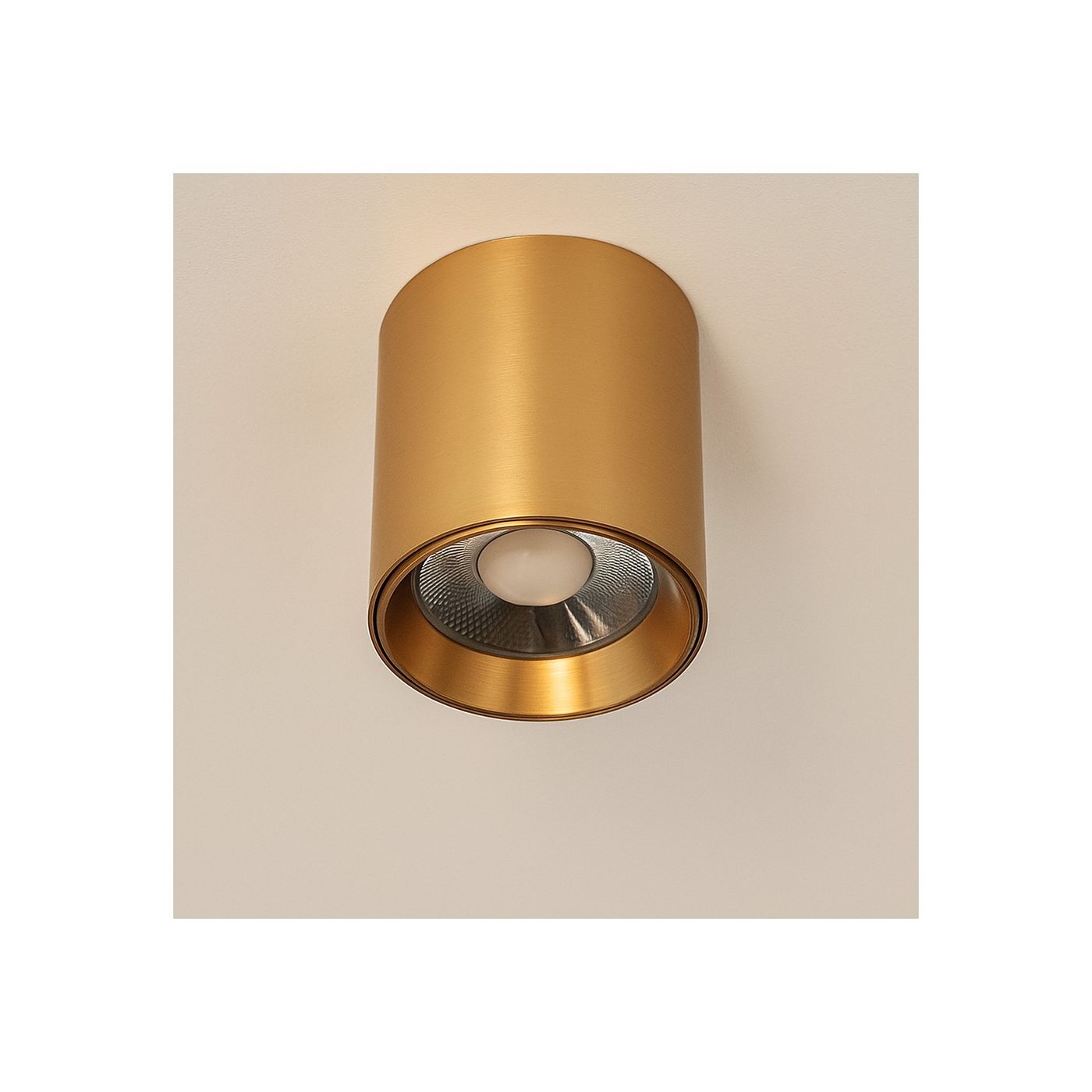 Lampa sufitowa LED 15W CCT w kolorze złotym, cylindryczny kształt z metaliczną powierzchnią. Widoczna soczewka z białym światłem w centralnej części, zamontowana na suficie. Tekstura matowa, elegancki design.